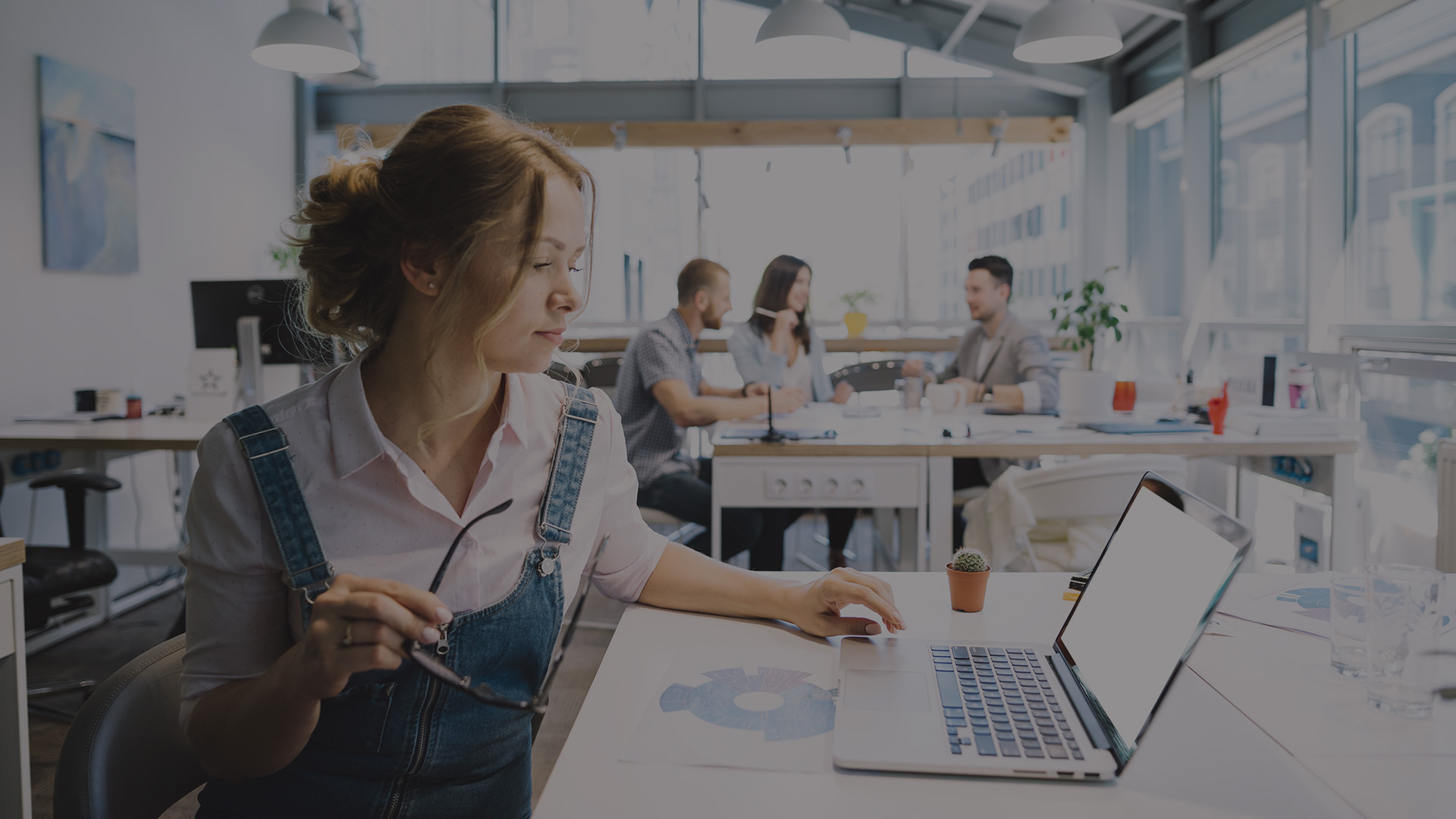 A woman working on a laptop in a modern office.