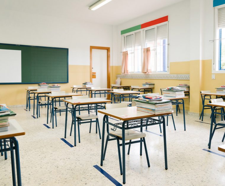 Empty classroom with desks and chairs arranged neatly.