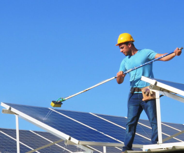 Worker cleaning solar panels on a sunny day.