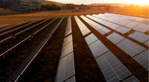 A woman with red hair working on a laptop in a bright, modern room.