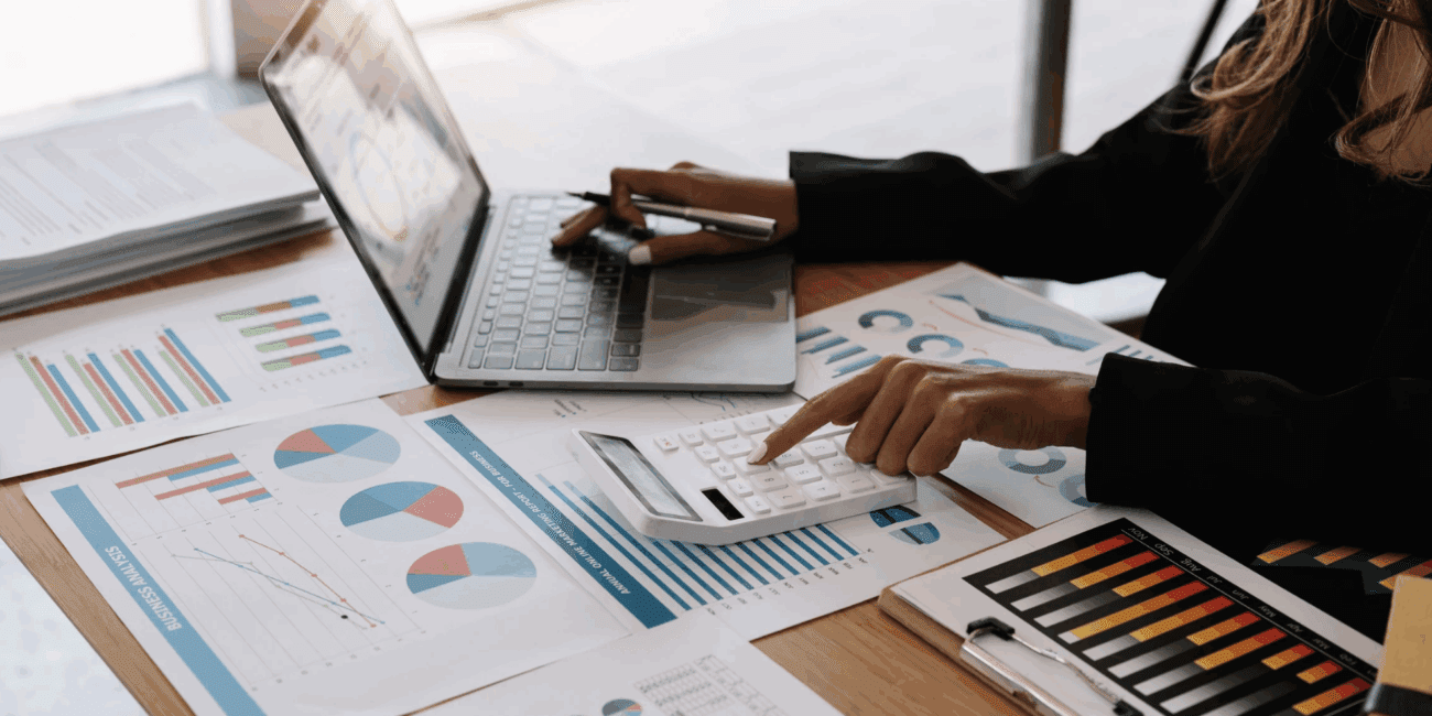 Person analyzing financial charts with a laptop and pen.